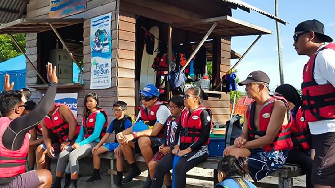 Group receiving safety briefing for jet ski experience in Langkawi, wearing life jackets.