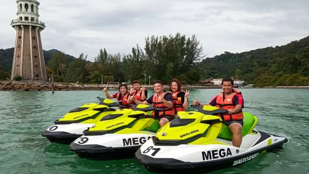 Group enjoying jet ski ride near lighthouse in Langkawi.