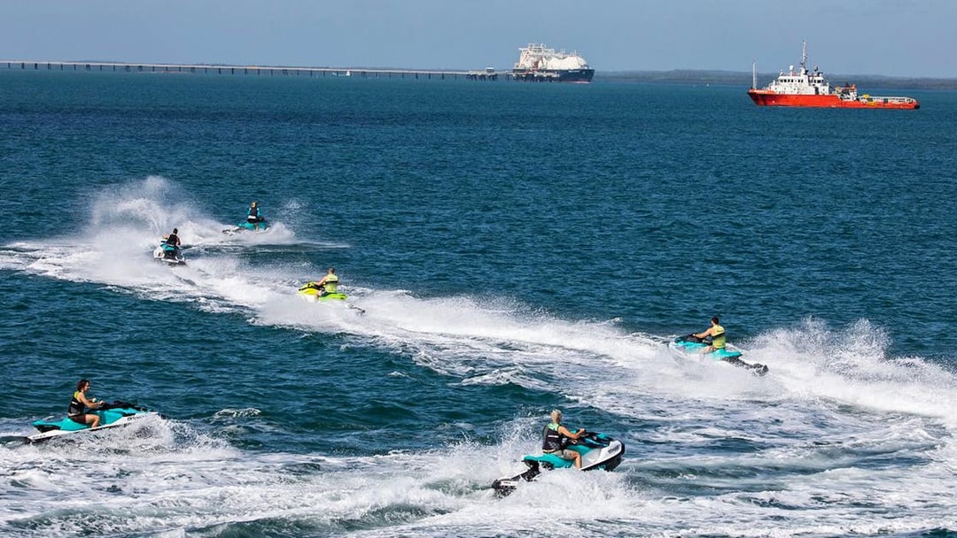 Jet skis speeding across the ocean in Darwin with ships in the background.