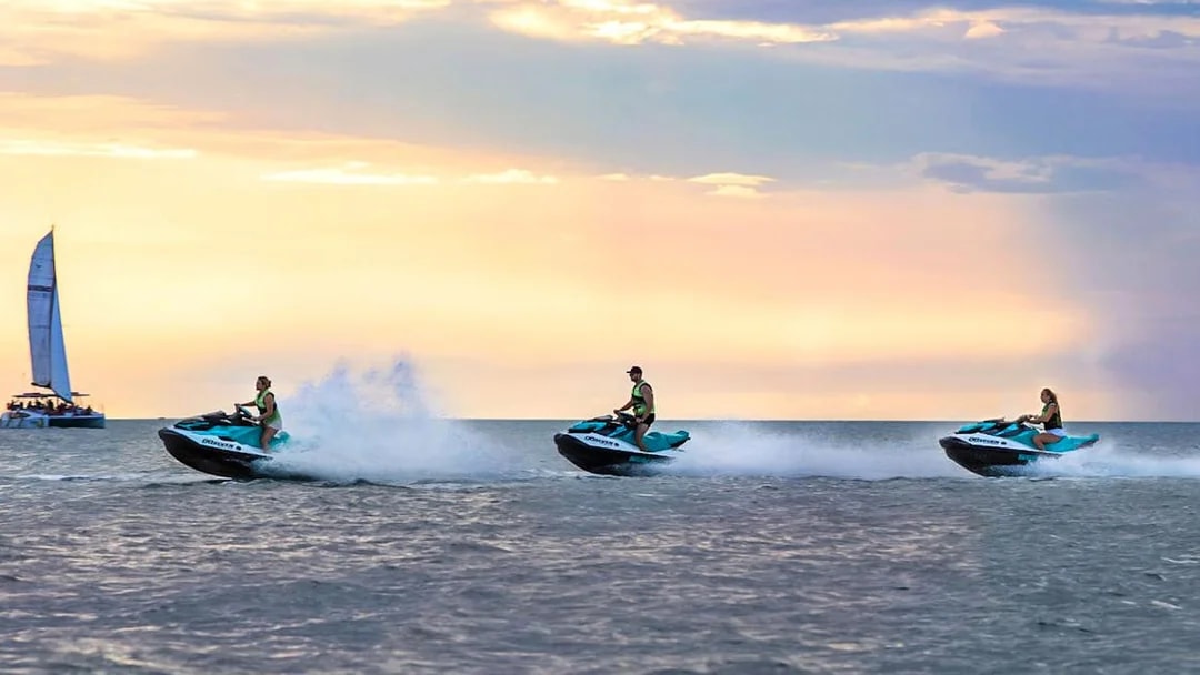 Jet skis speeding across the water at sunset during a tour in Darwin.