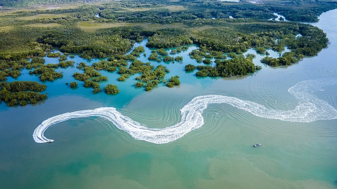 Jet ski creating wake trails in mangrove waters, Darwin.