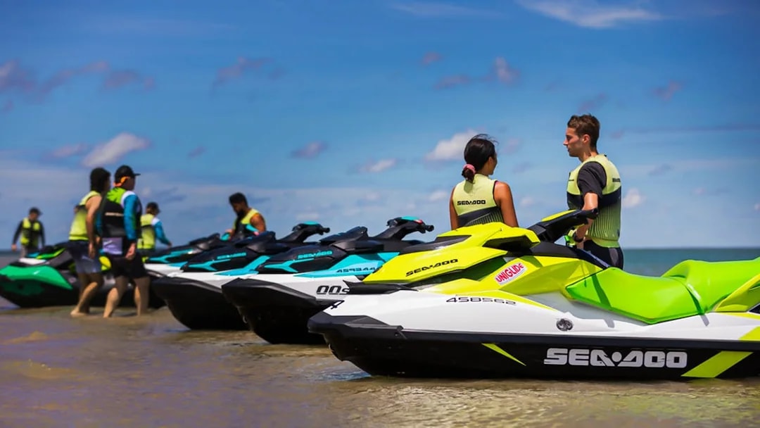 Jet skis lined up on the beach with people preparing for a tour in Darwin.