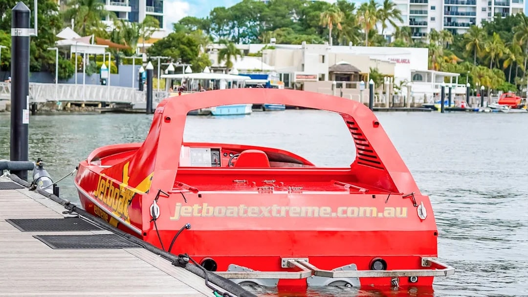 Red jet boat docked at marina, ready for Ultimate Jet Boat Ride and Surf Lesson.