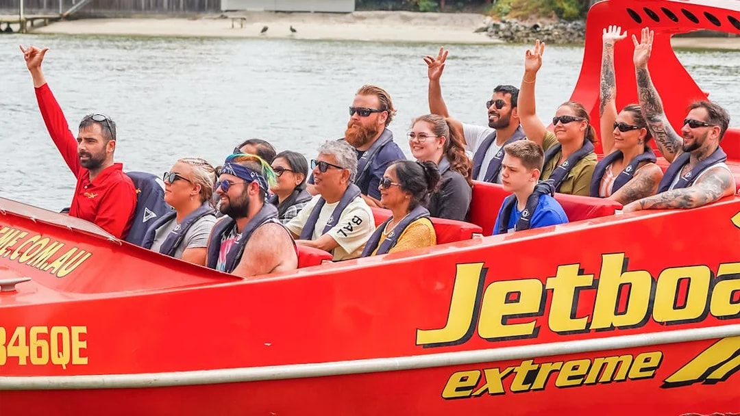 Group enjoying a thrilling jet boat ride on a river, part of the Ultimate Jet Boat Ride and Surf Lesson experience.