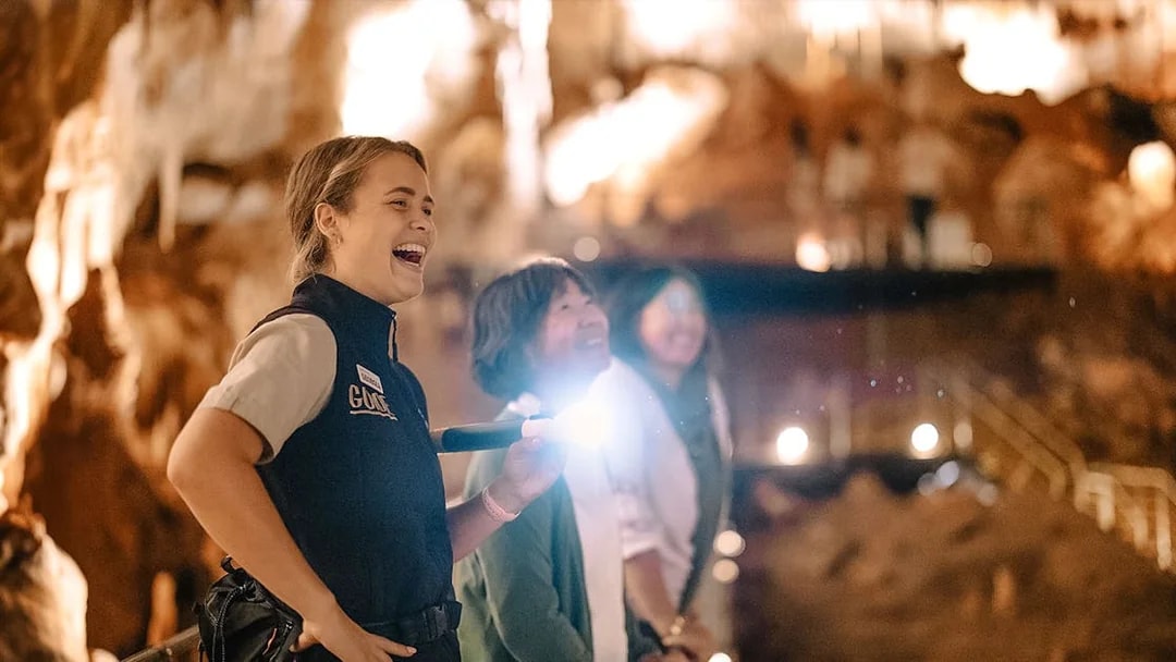 Guide leading a tour in Jewel Cave, Margaret River, with visitors observing stalactites.