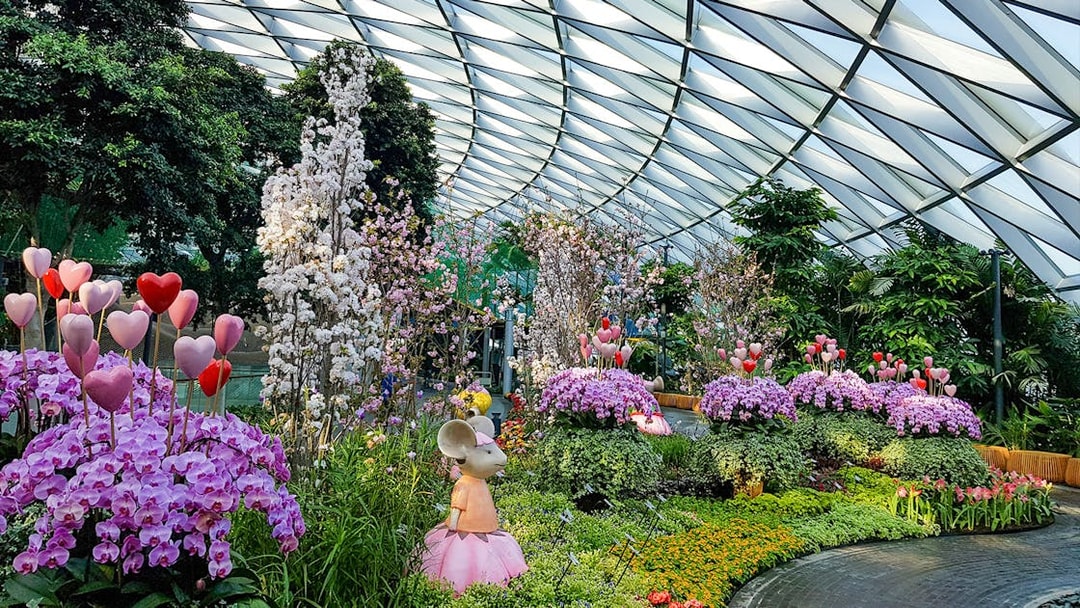 Jewel Changi Petal Garden with vibrant flowers and whimsical sculptures under a glass dome.