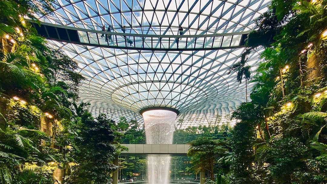 Jewel Changi Canopy Bridge with visitors walking above lush indoor garden, Singapore.
