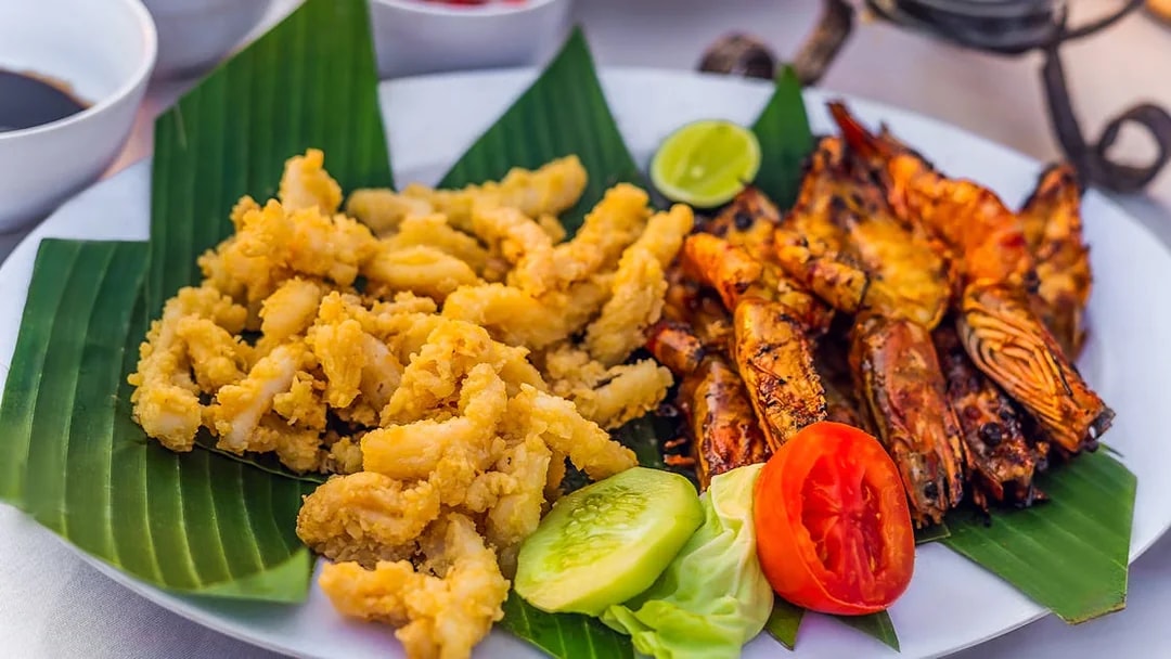 Grilled prawns and fried calamari on banana leaves, Jimbaran Bali seafood dinner.