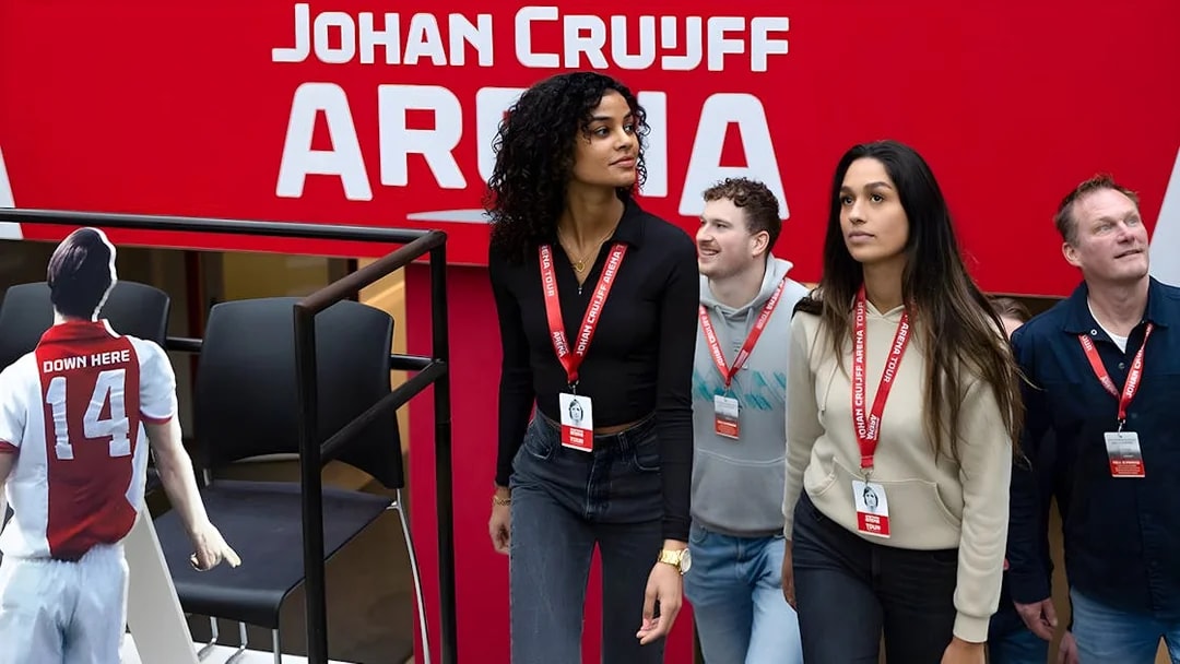 Visitors on Johan Cruijff ArenA Classic Tour wearing lanyards, near stadium seating.