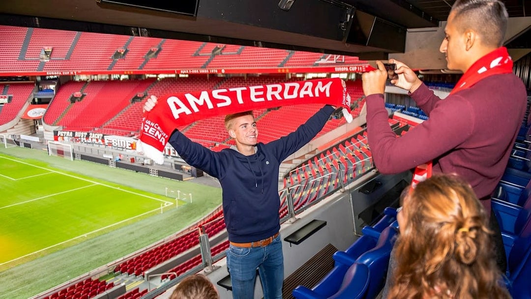 Man holding Amsterdam scarf at Johan Cruijff ArenA during VIP tour.