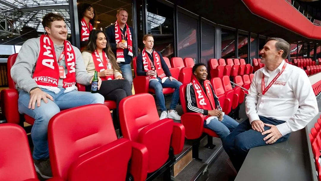 Visitors on a VIP tour at Johan Cruijff ArenA, Amsterdam, enjoying drinks and wearing scarves.