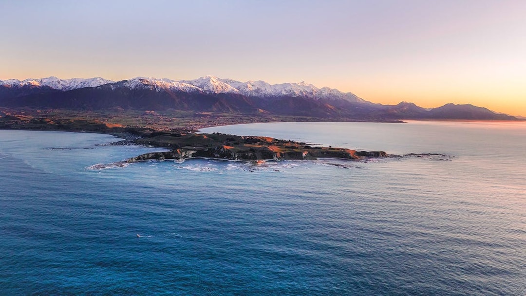 Aerial view of Kaikoura coastline with snowy mountains in the background.