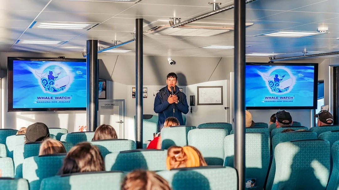 Guide giving a presentation on a whale watching cruise in Kaikoura, New Zealand.