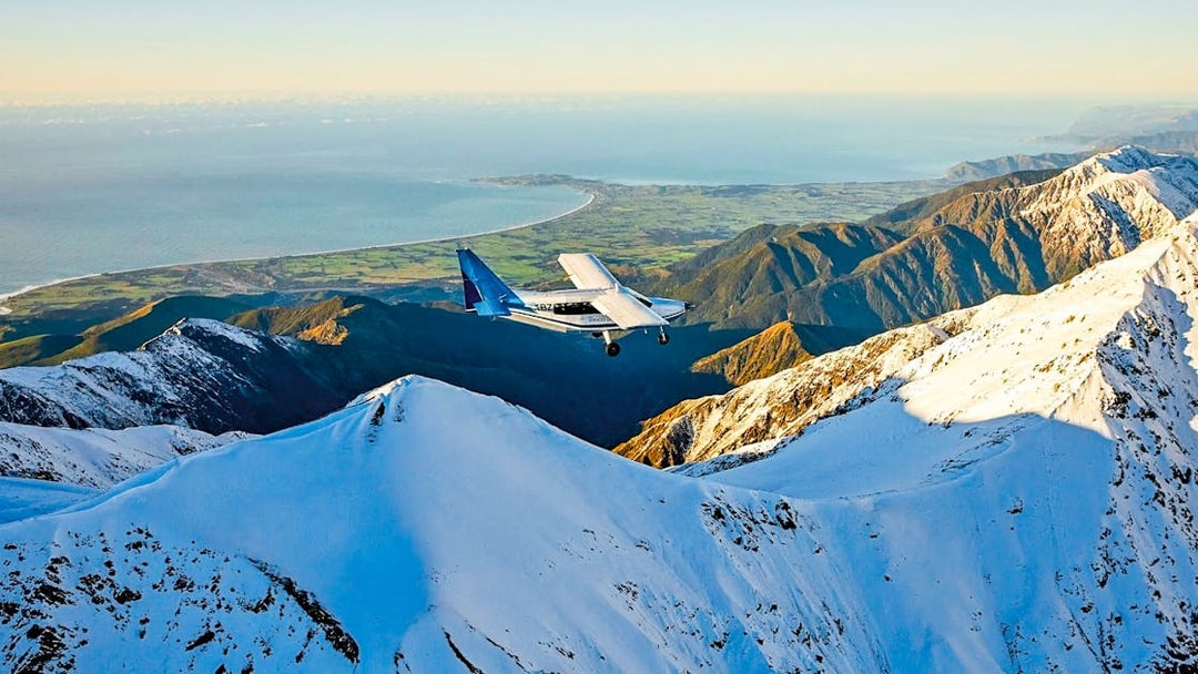 Aerial view of a plane flying over snowy mountains in Kaikoura, New Zealand.