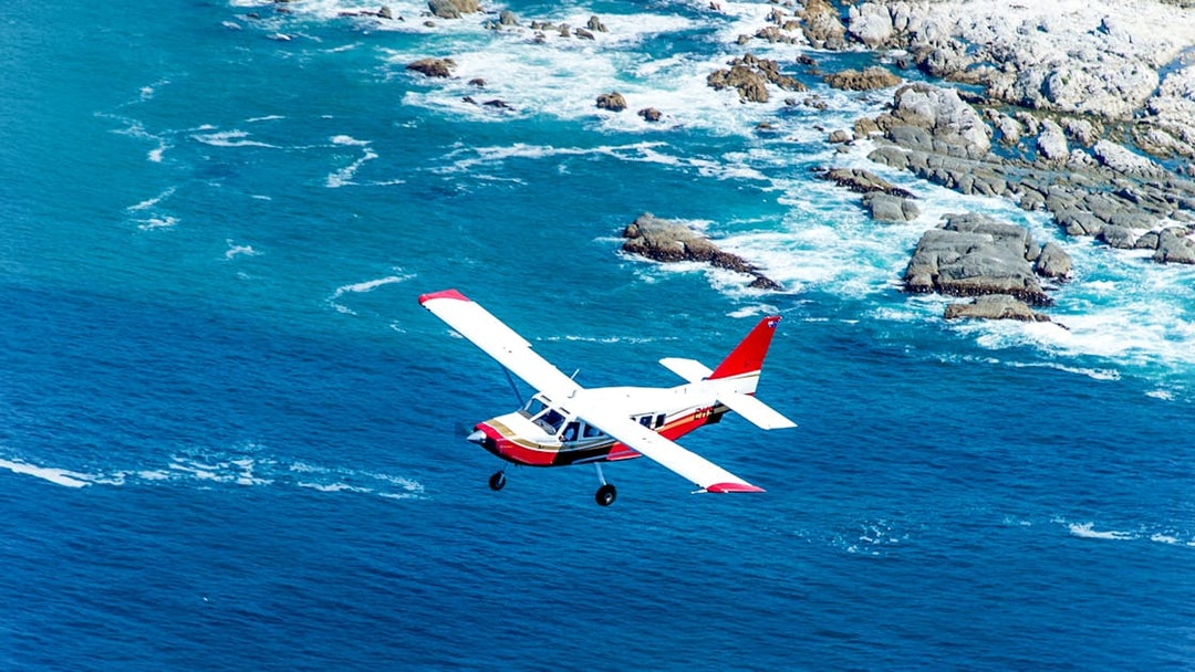 Small plane flying over Kaikoura coastline, New Zealand.