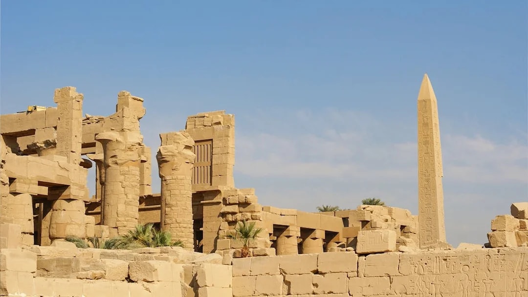 Karnak Temple ruins with ancient columns and obelisk under a clear sky in Luxor, Egypt.
