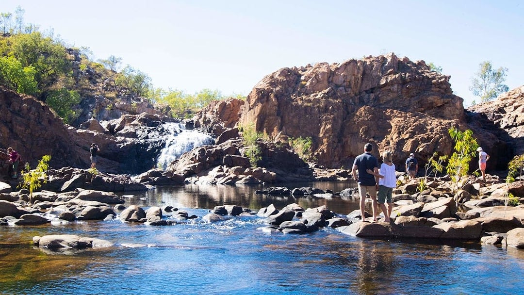 Visitors exploring Katherine Gorge with waterfall and rocky landscape.