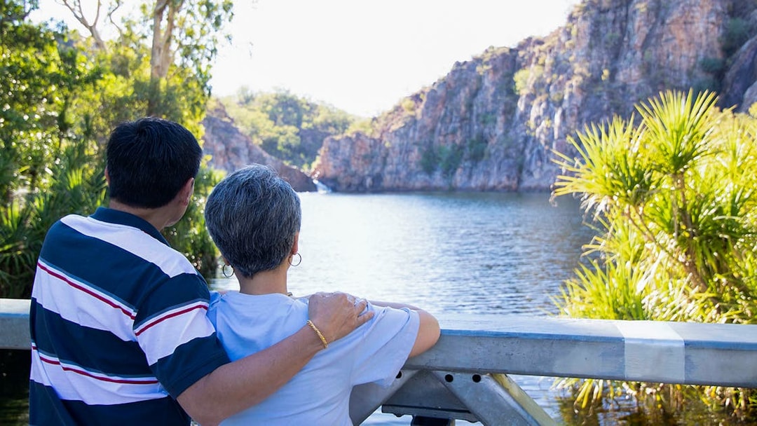 Couple enjoying view of Katherine Gorge from a lookout, surrounded by lush greenery.