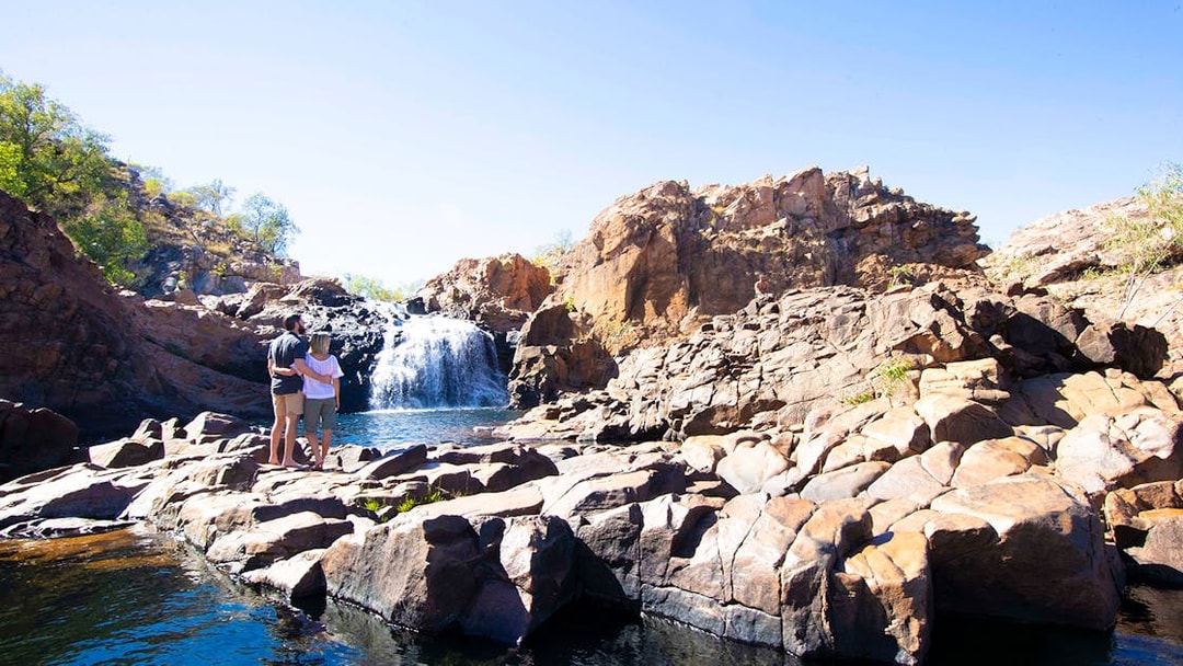 Couple standing on rocks overlooking waterfall at Katherine Gorge, Australia.