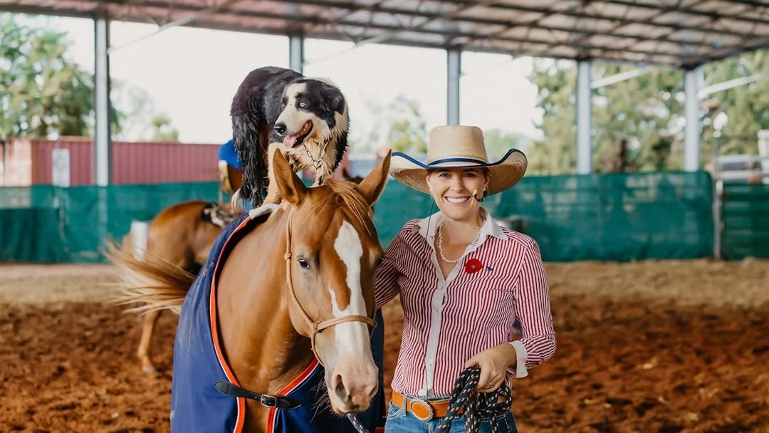Horse and dog performing with a smiling woman at Katherine Outback Experience show.