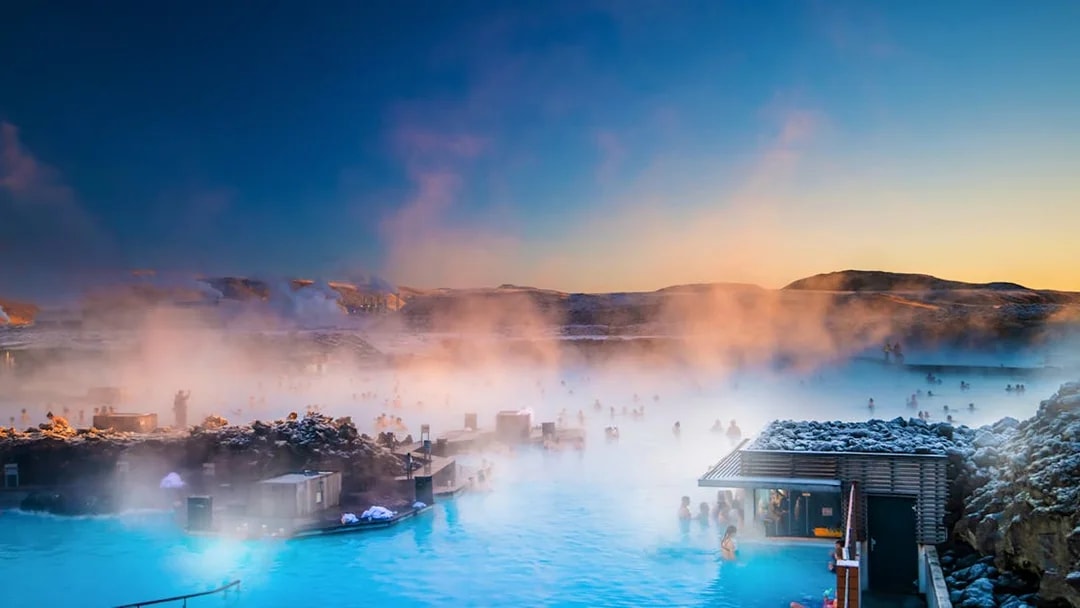 Tourists relaxing in Blue Lagoon hot spring spa, surrounded by Iceland's volcanic landscape.