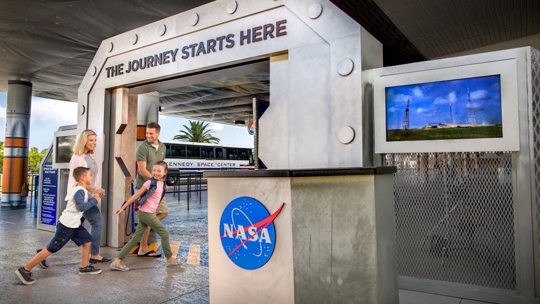 Family entering Kennedy Space Center entrance for VIP tour experience.