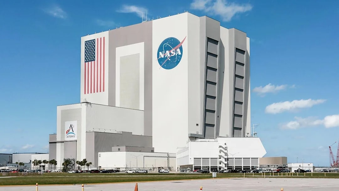 NASA Kennedy Space Center Vehicle Assembly Building with American flag and logo.