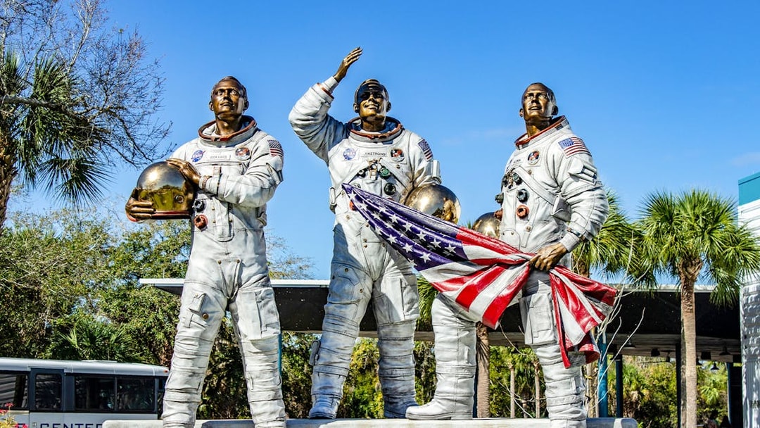 Statues of astronauts holding helmets and flag at Kennedy Space Center, USA.
