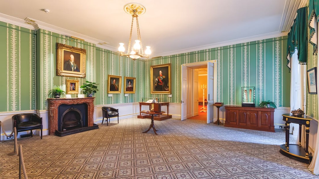 Kensington Palace interior with portraits and ornate fireplace.