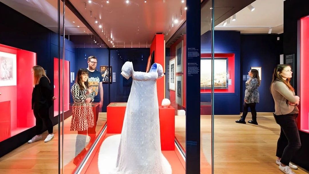 Visitors viewing a historical dress exhibit at Kensington Palace's Untold Lives tour.