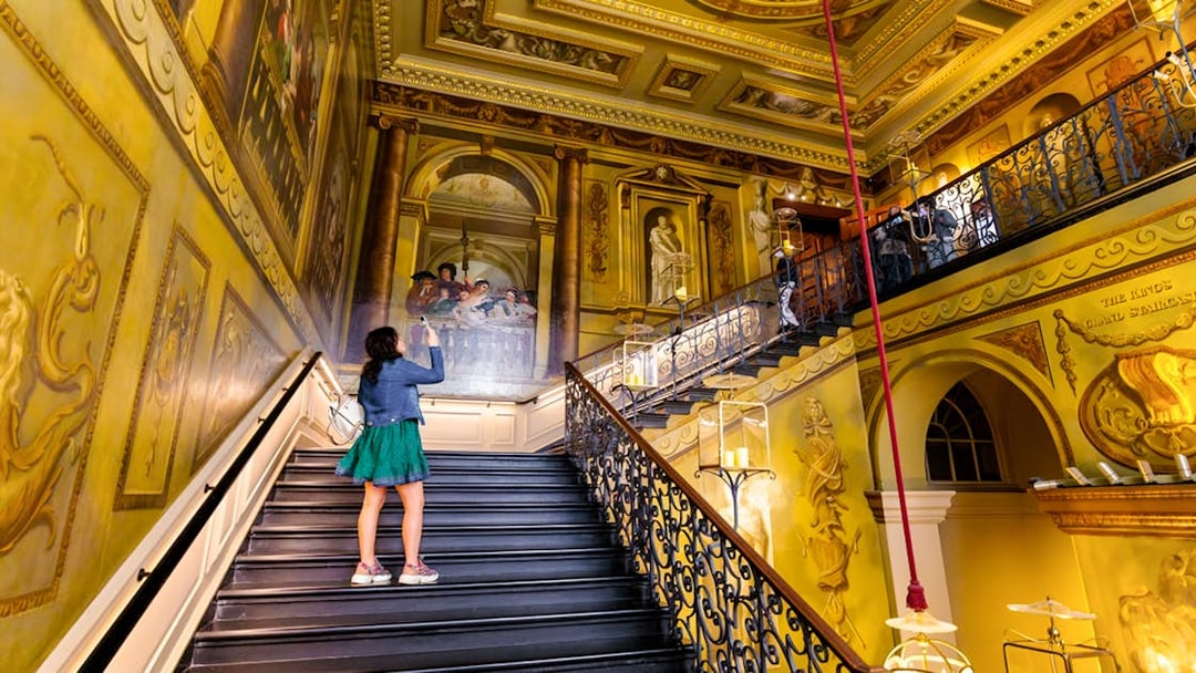 Tourists exploring ornate staircase at Kensington Palace, London.
