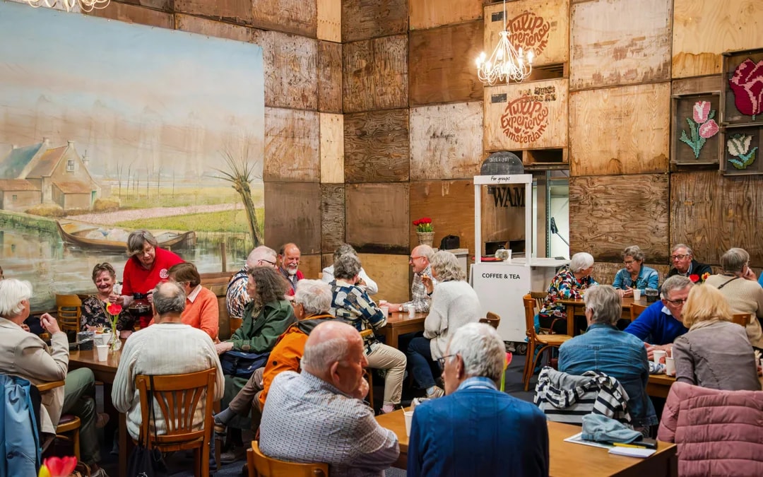 Group enjoying coffee at Tulip Experience Amsterdam with mural backdrop.