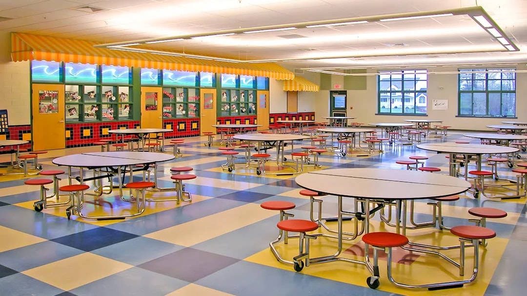 Colorful cafeteria with round tables and red stools at KidsSTOP Singapore.