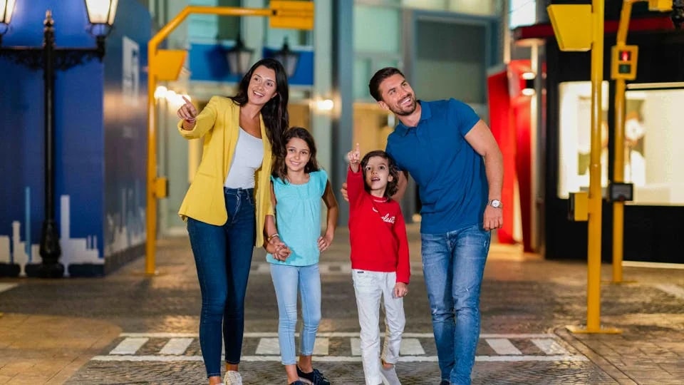 Family exploring KidZania Dubai, children pointing at attractions.