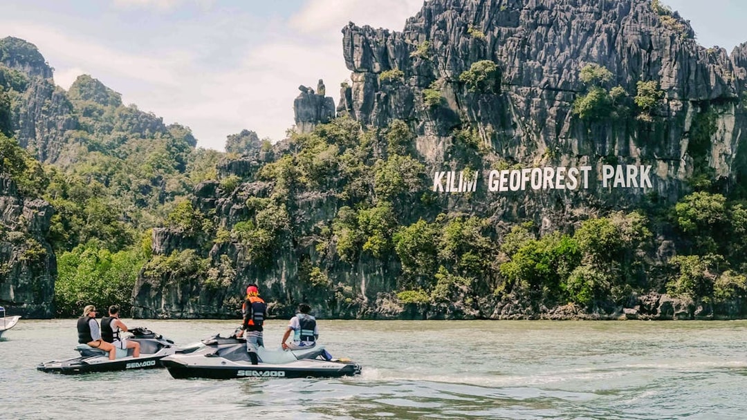 Jet skis near limestone cliffs at Kilim Geoforest Park, Langkawi.