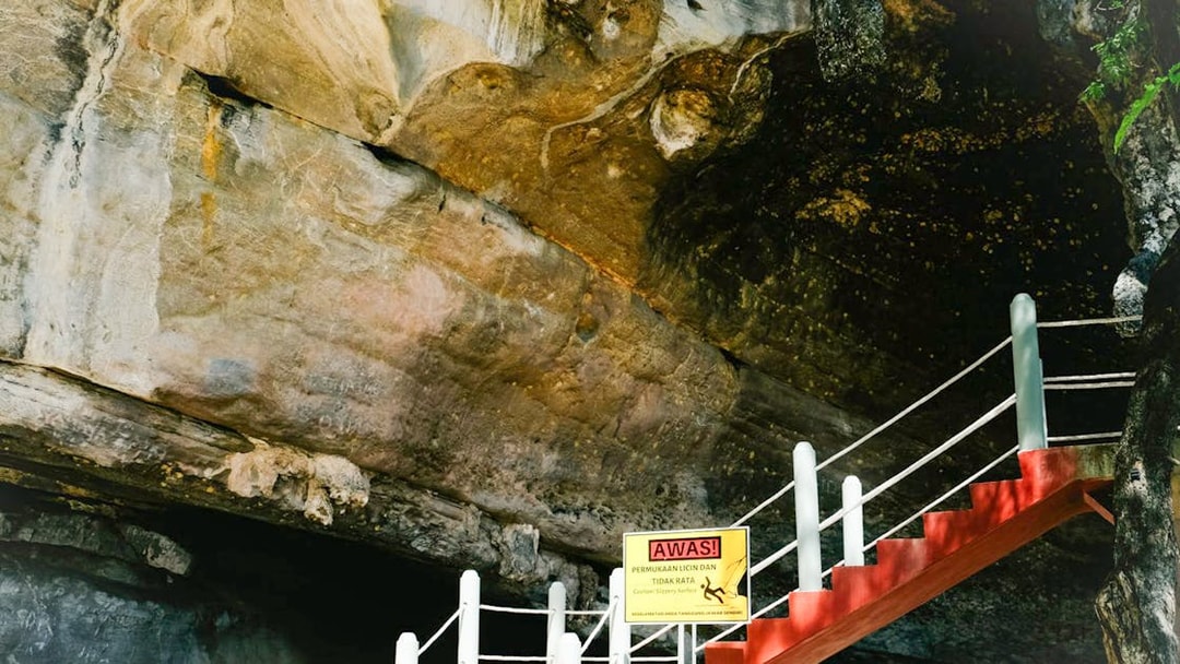 Staircase leading to cave entrance at Kilim Geopark, Langkawi, with caution sign.