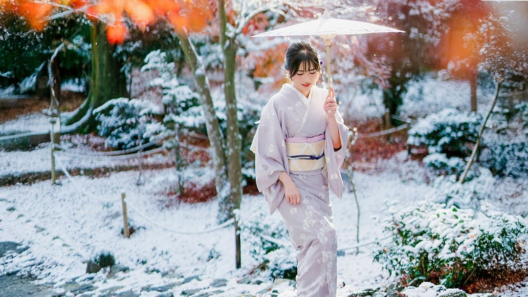 Woman in kimono with umbrella in snowy Arashiyama, Kyoto.