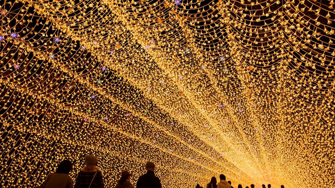 Tunnel of golden lights at Nabana no Sato, Japan, viewed by visitors, accessible with Kintetsu Rail Pass.