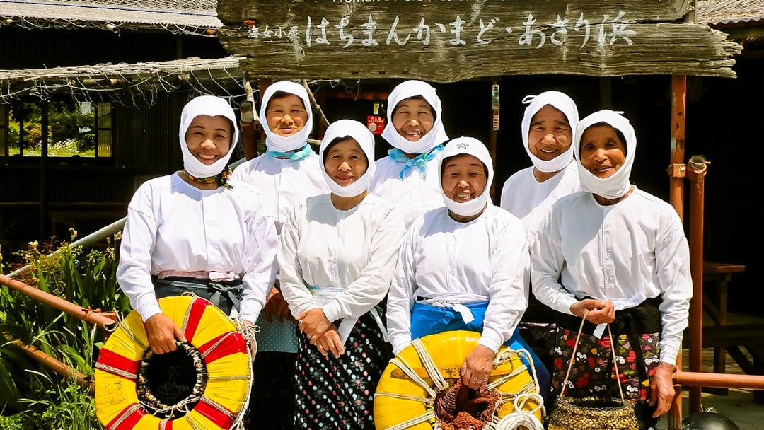 Ama divers in traditional attire holding flotation devices in Japan.