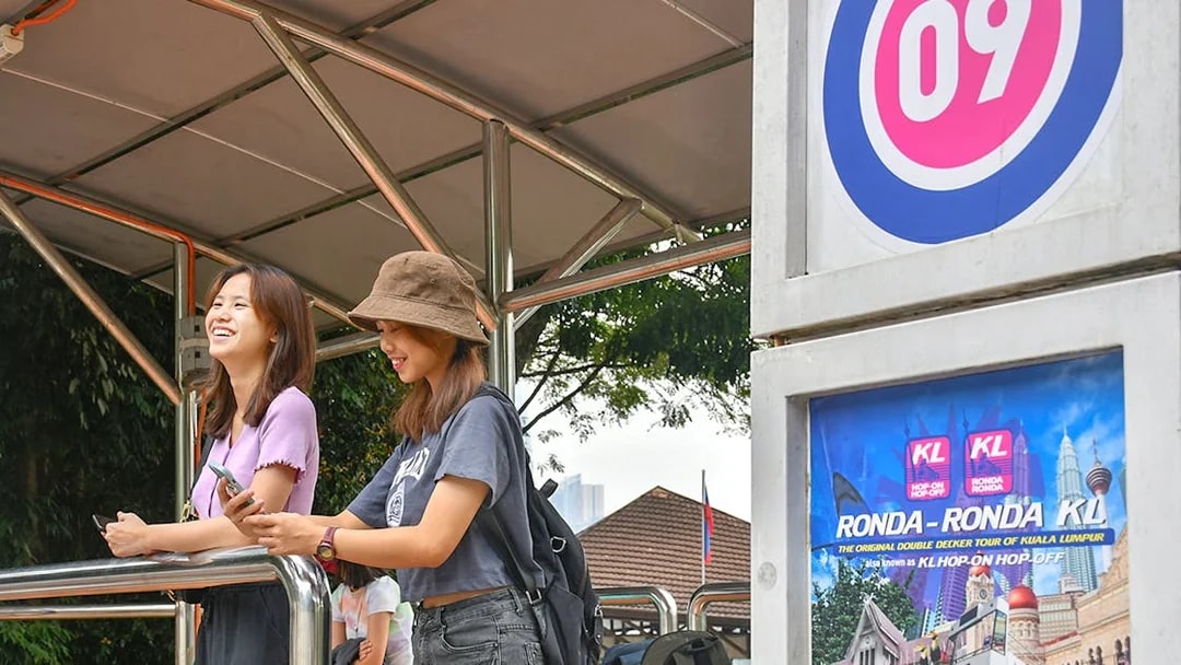 Passengers waiting at a Kuala Lumpur Hop-On Hop-Off tour stop.