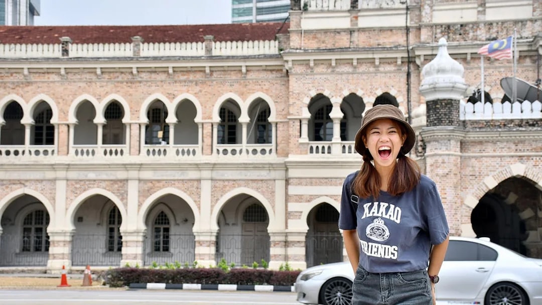 Tourist smiling in front of Sultan Abdul Samad Building, Kuala Lumpur.