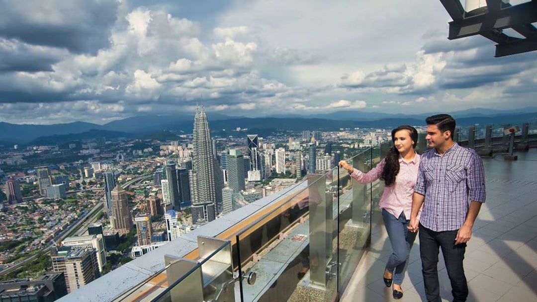 Couple enjoying city view from KL Tower observation deck, Kuala Lumpur.