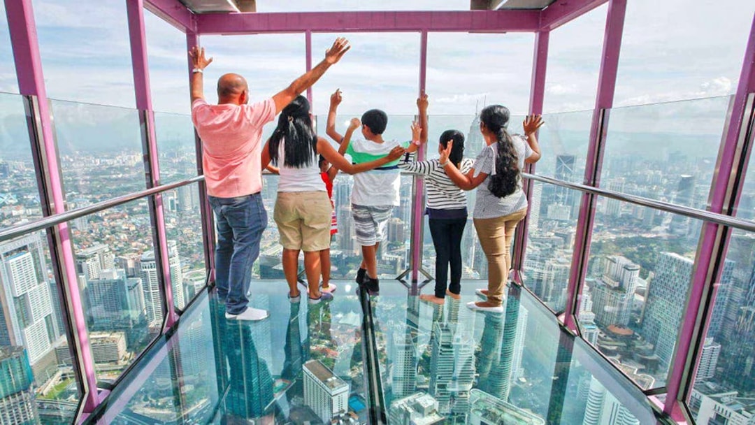 Visitors enjoying panoramic views from KL Tower's glass observation deck in Kuala Lumpur.