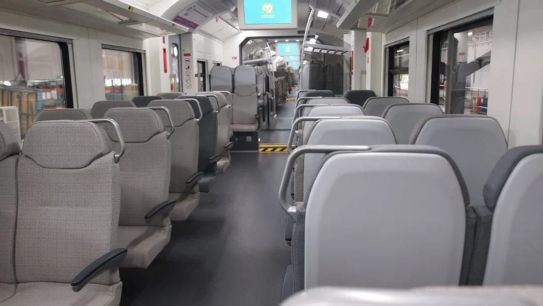 Interior of KLIA Ekspres train with empty seats and digital screens.