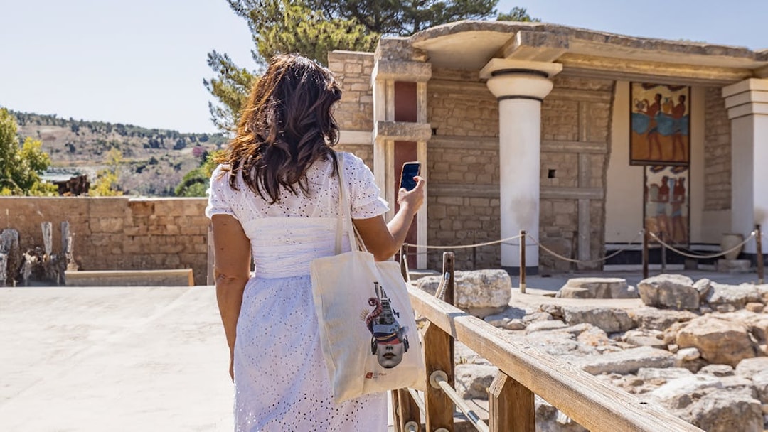 Woman exploring Knossos Palace with self-guided audio tour in English, French, and Italian.