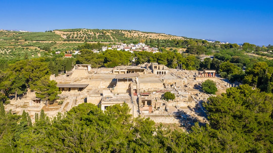 Knossos Palace ruins surrounded by lush greenery, Crete, Greece.
