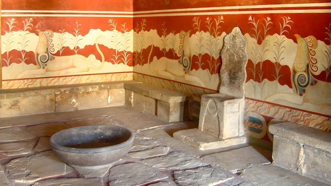 Throne room at Knossos Palace with stone seat and frescoes.