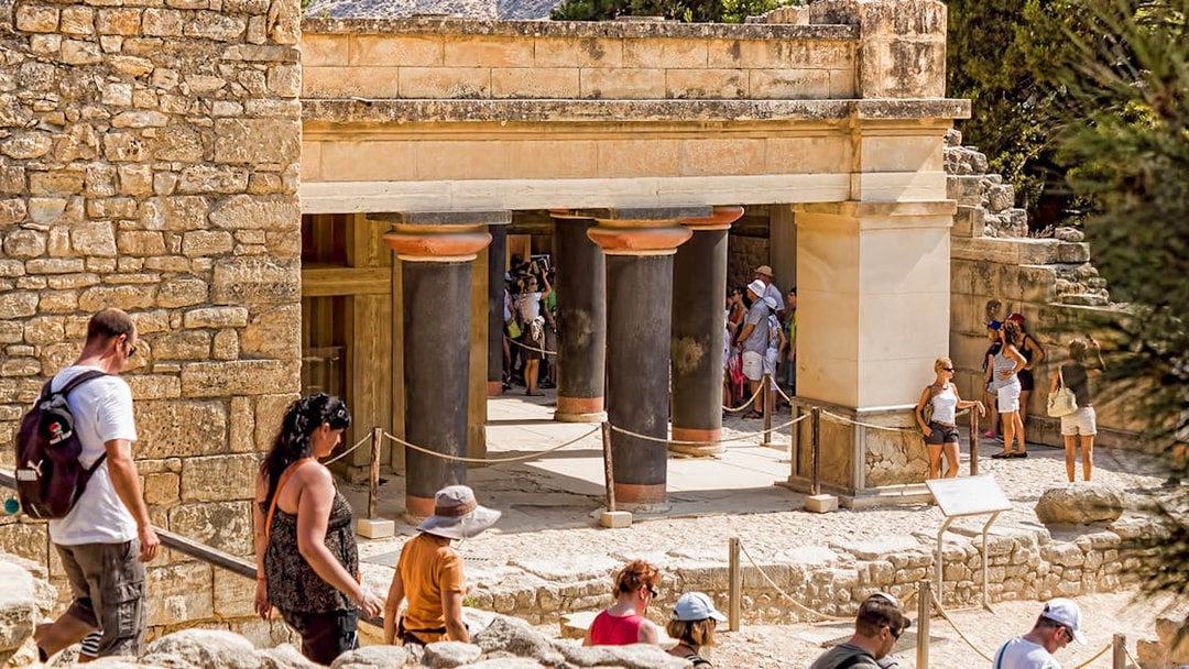 Guided tour group exploring Knossos Palace Archaeological Site in Crete.