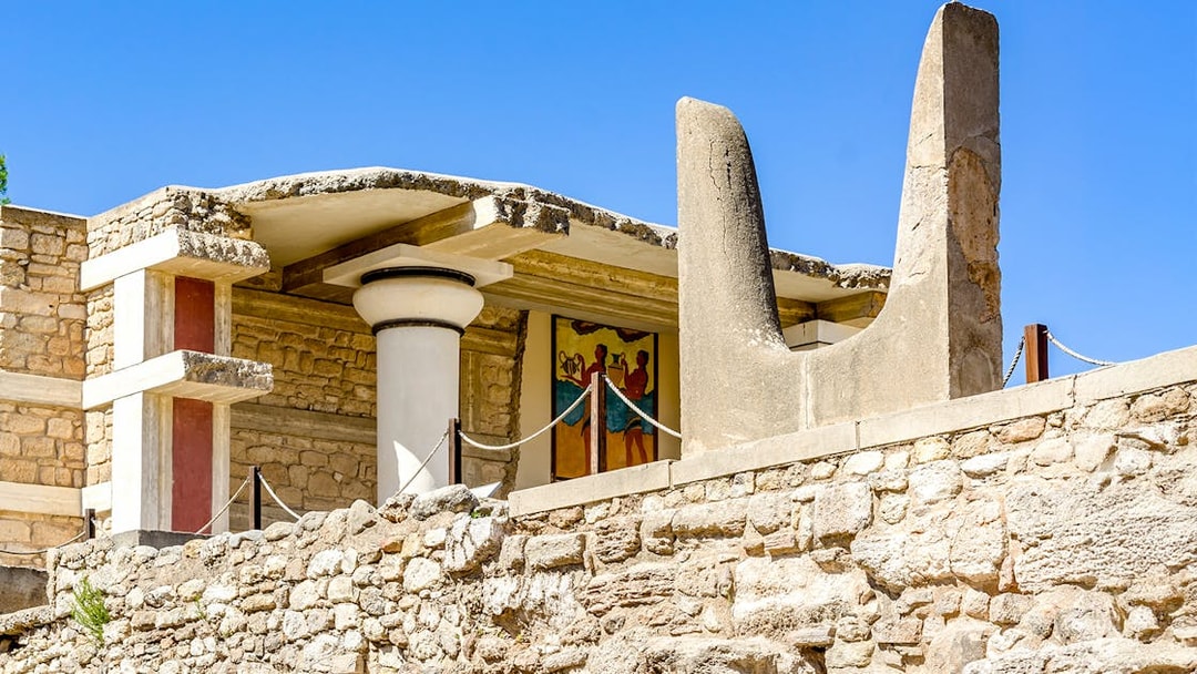 Bulls Horns sculpture at Knossos Palace, Crete, with ancient fresco in background.