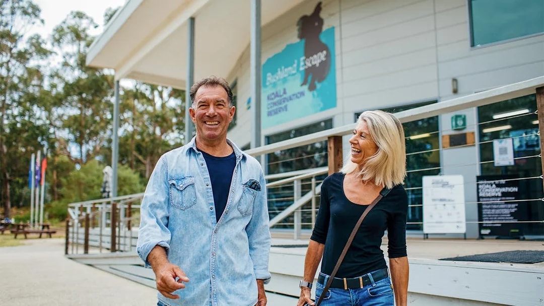 Visitors smiling outside Koala Conservation Reserve entrance, Phillip Island Nature Parks.